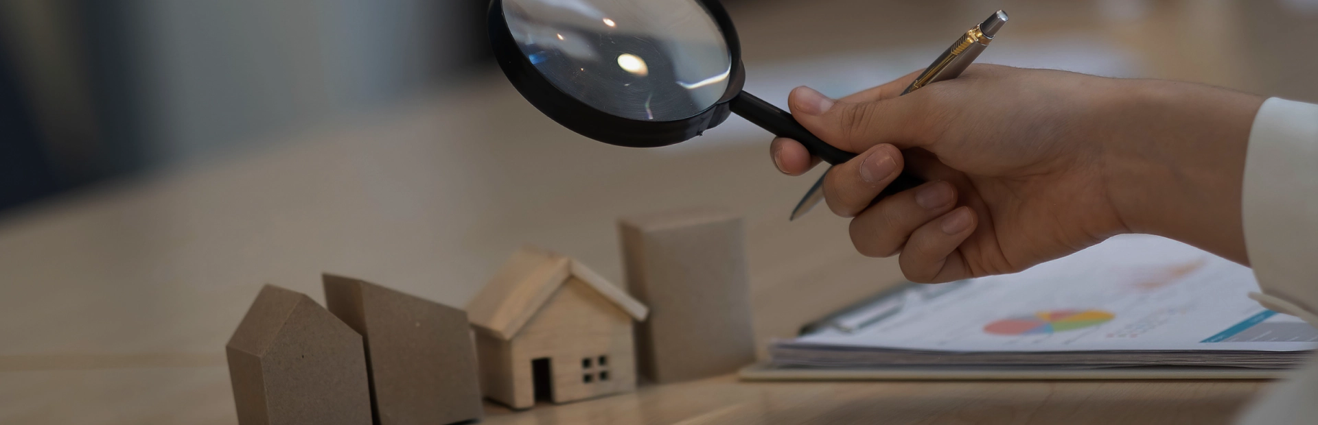 someone holding a magnifying glass on a house model